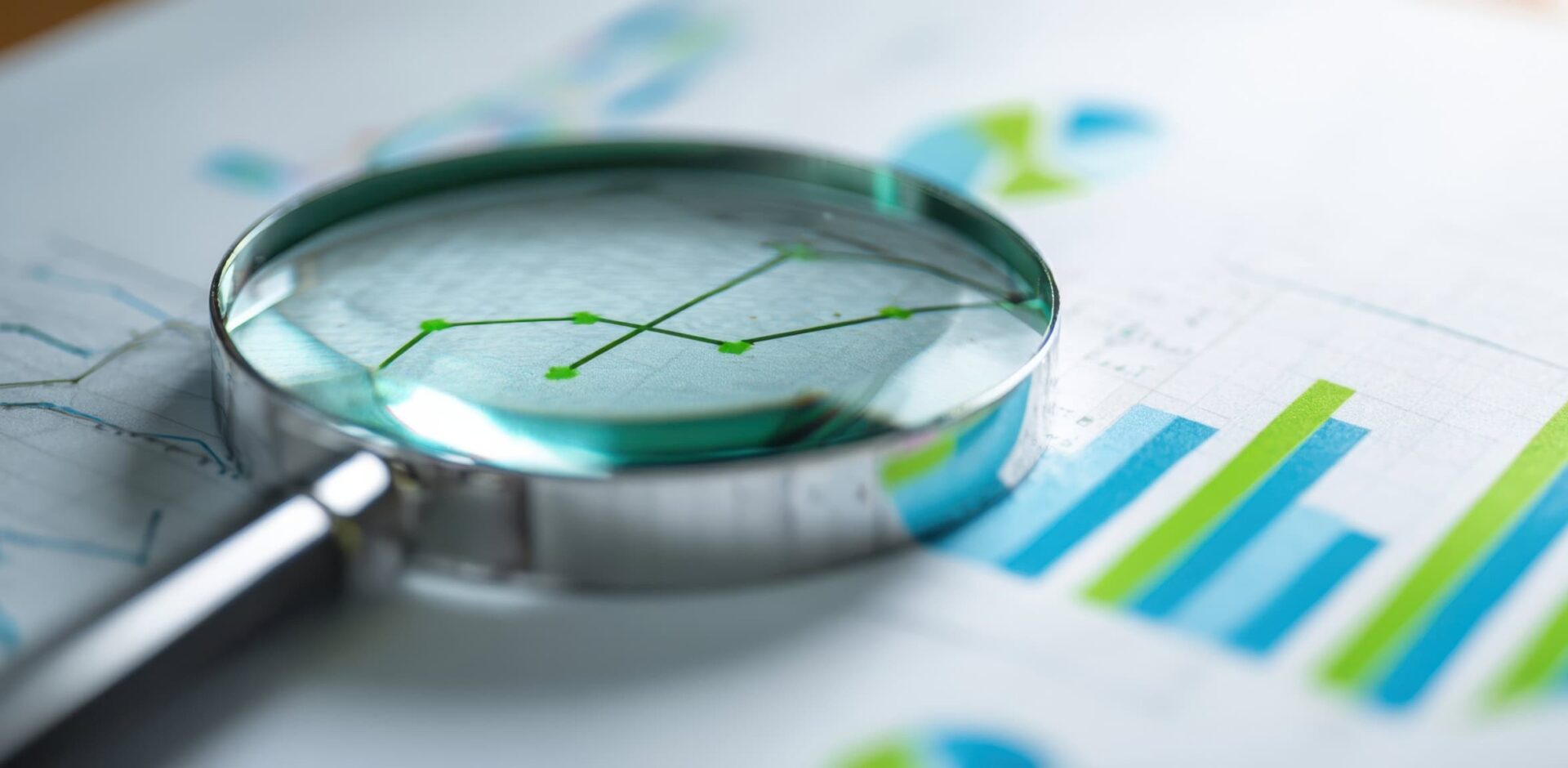 The magnifying glass highlighting financial charts and data analysis for business insight. By Studio Nova - AdobeStock. AI-generated