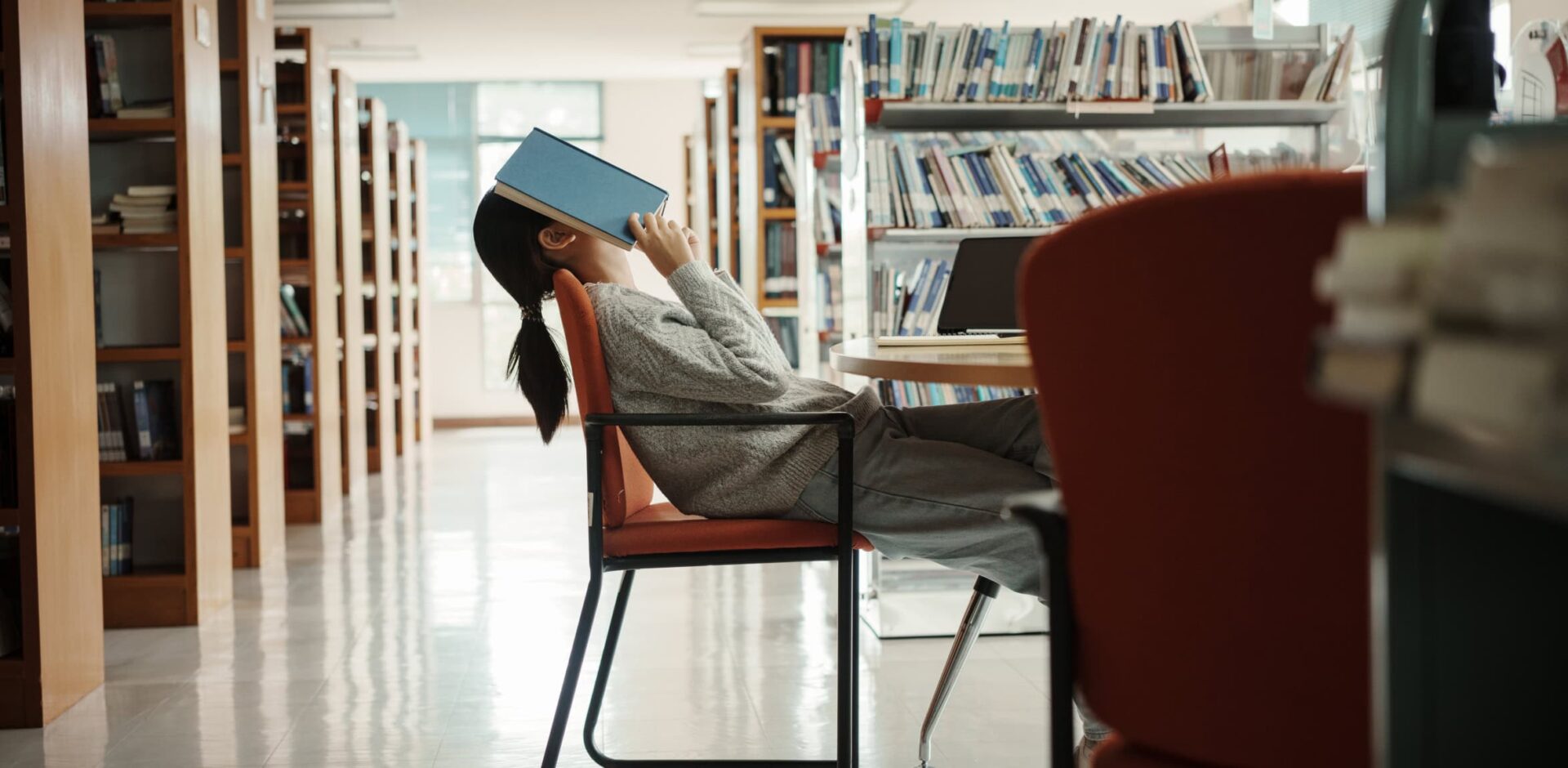 Asian student woman read books in library at university. Young girl stress tired have problem while study hard. Sadness concept. By Thanumporn - AdobeStock